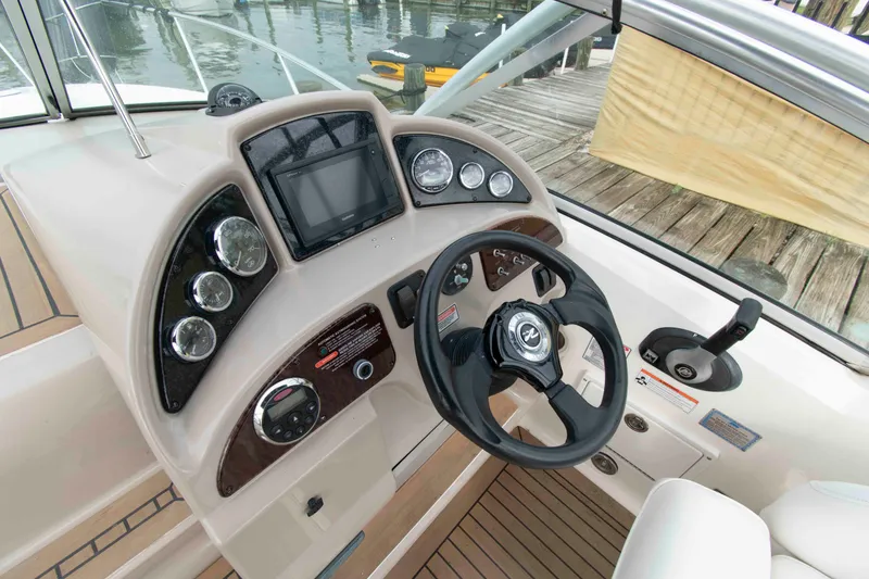 Slide: The Image of 2007 Sea Ray 270 Amberjack helm with steering wheel, gauges, and controls by the dock. - 6