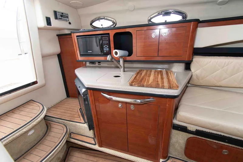 Slide: The Image of 2007 Sea Ray 270 Amberjack cabin with kitchenette, featuring wood cabinetry and modern appliances. - 10