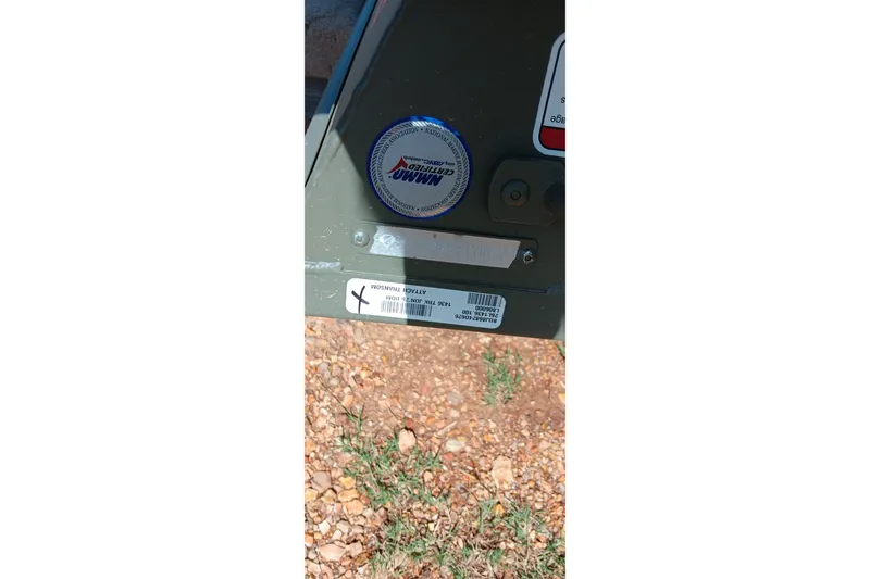 Slide: The Image of 2026 Tracker Grizzly 1436 Jon boat detail with labels and cap on rocky ground. - 6