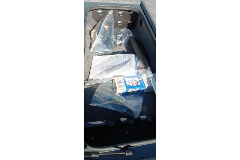 Slide: The Image of Storage compartment of 2026 Ranger RT198P boat with packaged items and documents. - 16