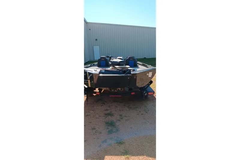 Slide: The Image of 2026 Ranger RT198P boat parked outdoors, rear view, near a metal building. - 2