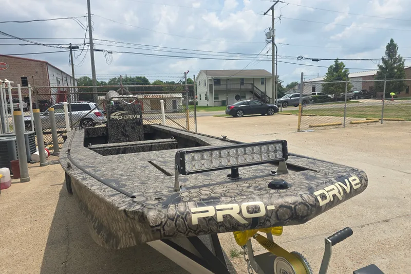 Slide: The Image of 2026 Pro Drive 2054 X Series TD CC boat with camouflage design in a parking area. - 10