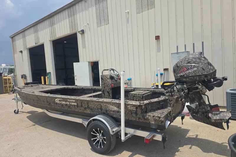 Slide: The Image of 2026 Pro Drive 2054 X Series TD CC boat with camouflage design, parked outside a garage. - 5