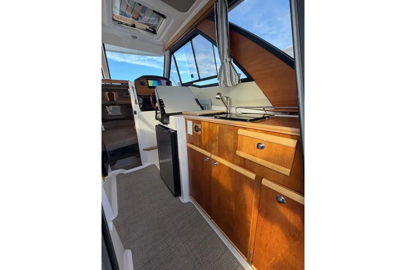 Slide: The Image of 2024 Cutwater C-248 Coupe interior with wooden cabinetry and compact kitchen area. - 14