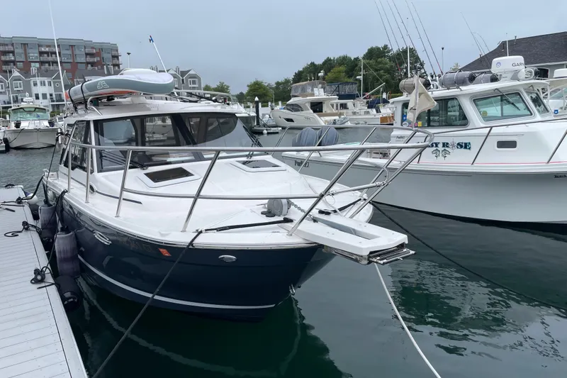 Slide: The Image of 2024 Cutwater C-248 Coupe docked at a marina, surrounded by other boats. - 2
