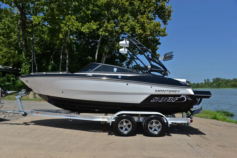 Slide: The Image of 2020 Monterey 218 Surf boat on trailer by a lake, surrounded by trees. - 11
