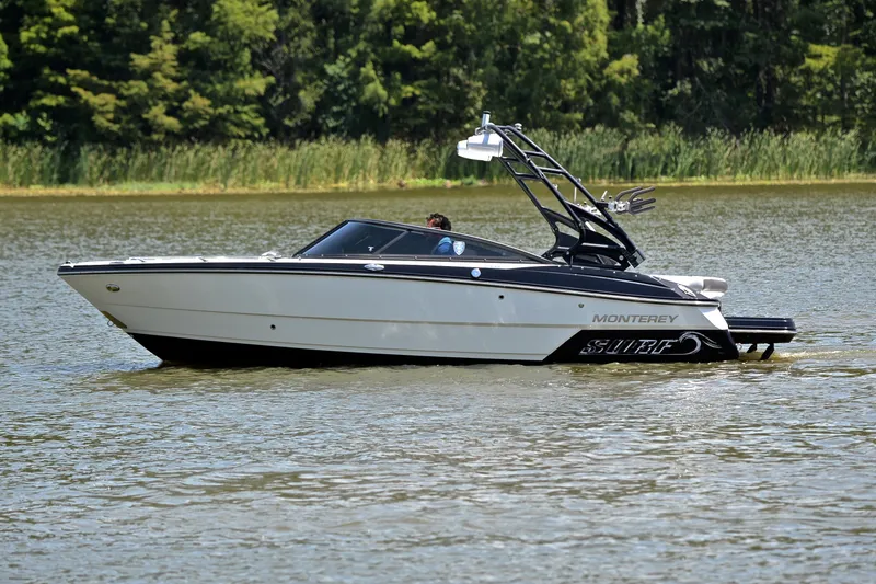 Slide: The Image of 2020 Monterey 218 Surf boat cruising on a calm lake with lush greenery. - 9