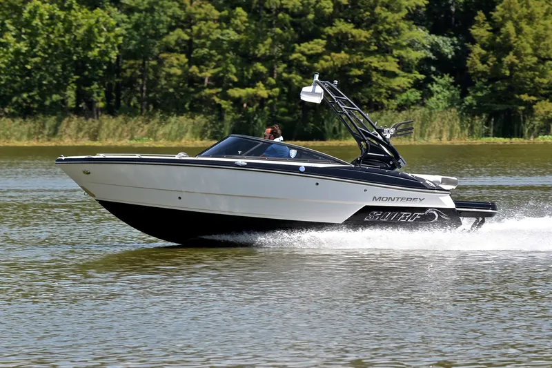 Slide: The Image of 2020 Monterey 218 Surf boat cruising on a lake with lush green trees. - 2