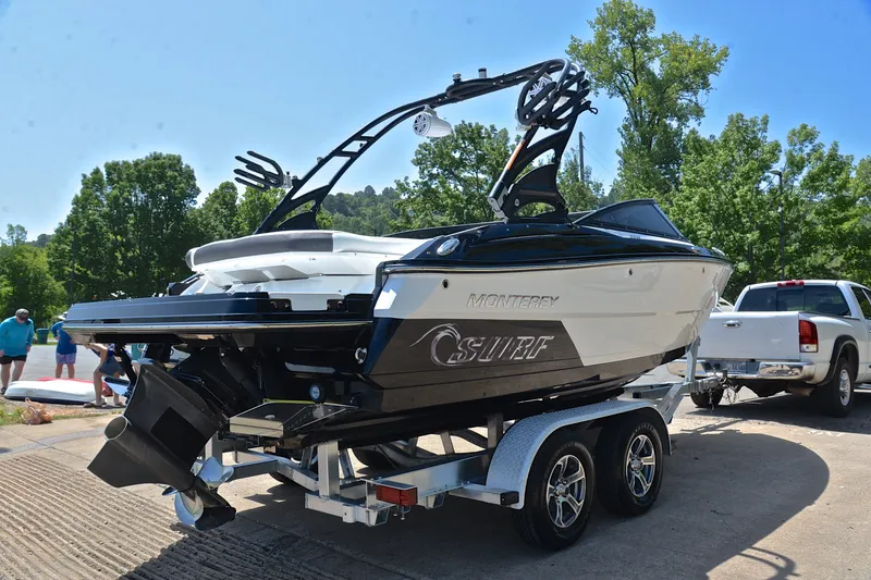 Slide: The Image of 2020 Monterey 218 Surf boat on trailer, parked outdoors with trees in background. - 14