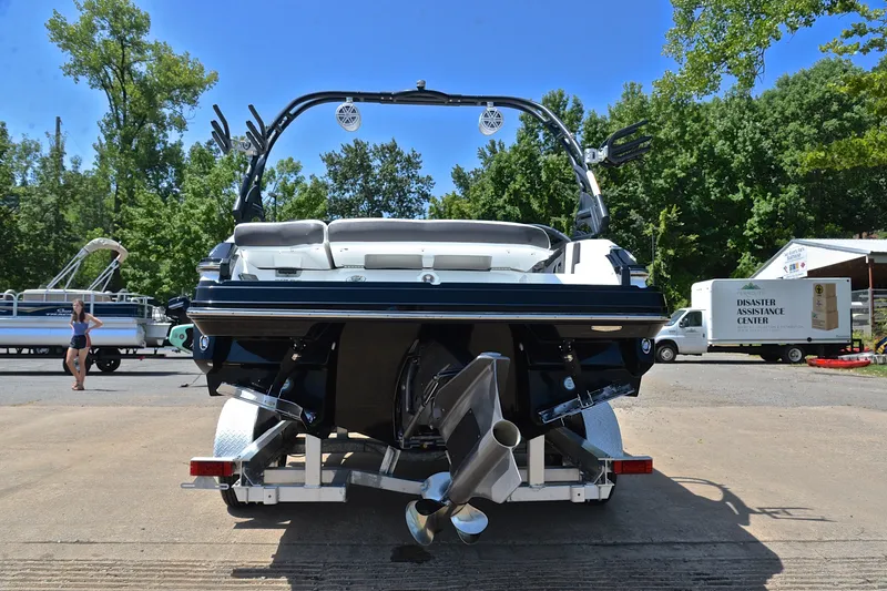 Slide: The Image of 2020 Monterey 218 Surf boat on trailer, parked outdoors with trees in background. - 13