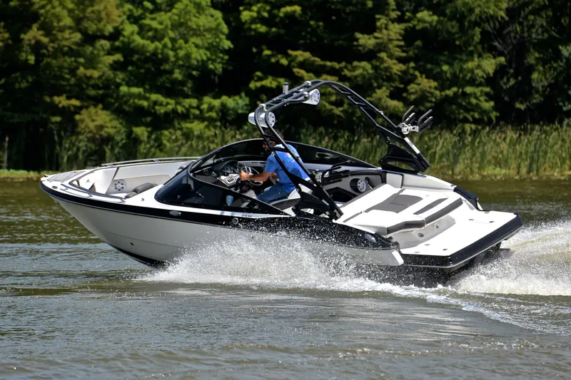 Slide: The Image of 2020 Monterey 218 Surf boat cruising on a lake with lush greenery in the background. - 6