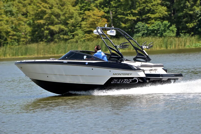 Slide: The Image of 2020 Monterey 218 Surf boat cruising on a lake with lush green trees in the background. - 5
