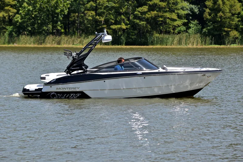 Slide: The Image of 2020 Monterey 218 Surf boat cruising on a calm lake with lush greenery. - 7