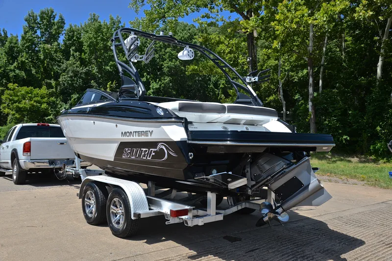 Slide: The Image of 2020 Monterey 218 Surf boat on trailer, parked near lush green trees. - 12