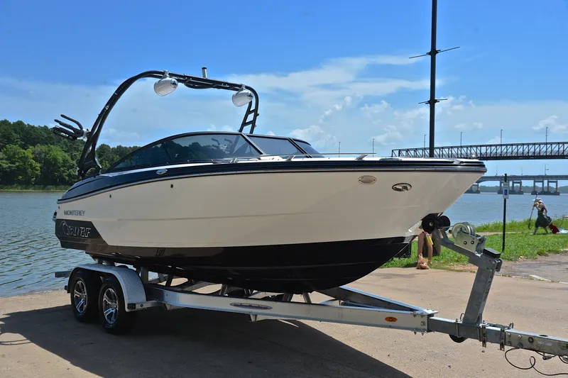 Slide: The Image of 2020 Monterey 218 Surf boat on trailer by a lake, under clear blue sky. - 16