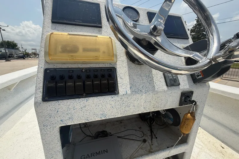 Slide: The Image of Control panel of a 2006 Reno Skiff 23ft boat with steering wheel and switches. - 13