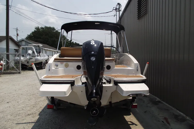 Slide: The Image of 2020 Bayliner DX 2000 boat with outboard motor, parked outdoors. - 3