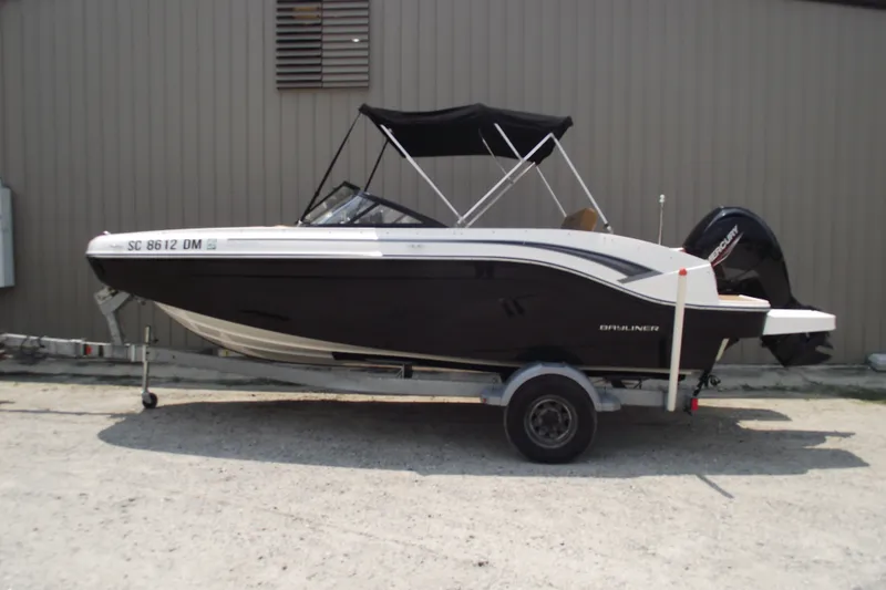 The Image of 2020 Bayliner DX 2000 boat on trailer, black and white design, parked outdoors. - 0