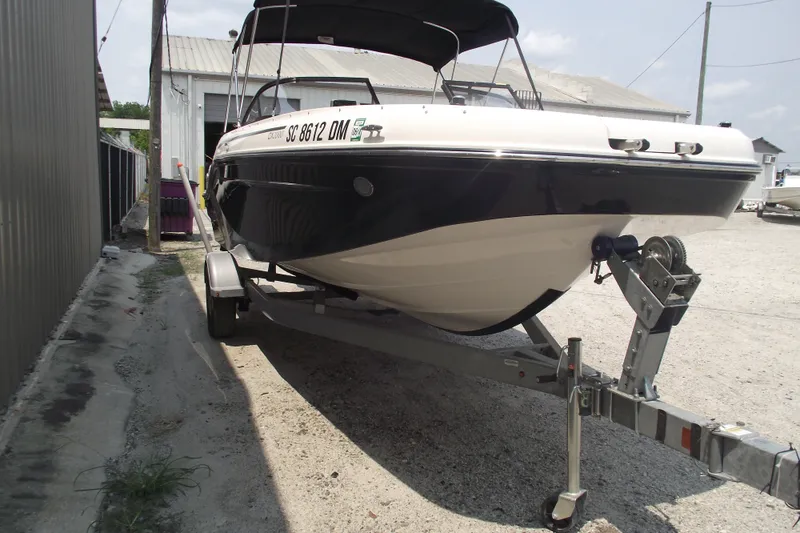 Slide: The Image of 2020 Bayliner DX 2000 boat on trailer, parked outdoors near buildings. - 2