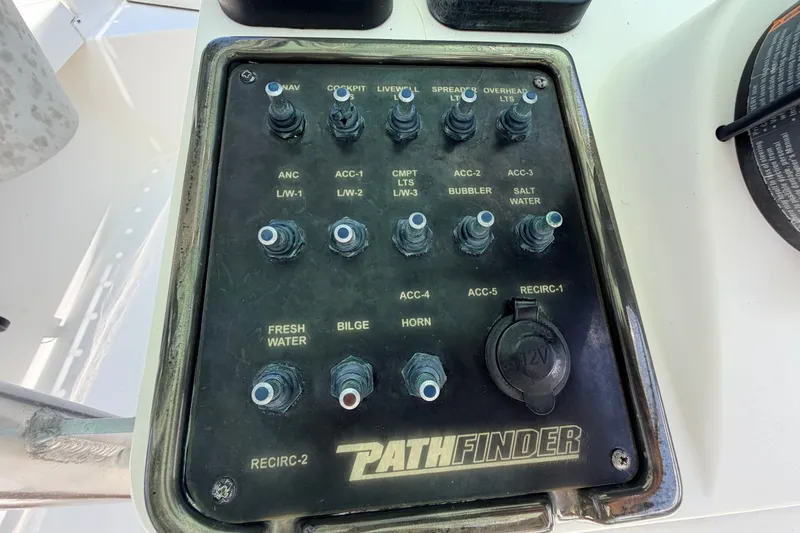 Slide: The Image of Control panel of a 2013 Pathfinder 2300 HPS boat with various switches and a 12V outlet. - 41