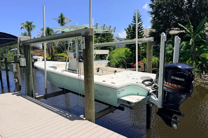The Image of 2015 Pathfinder 2300 HPS boat with Yamaha engine on lift, surrounded by tropical scenery. - 1