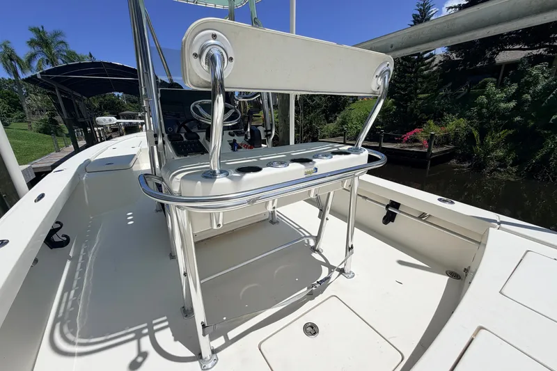 Slide: The Image of 2015 Pathfinder 2300 HPS boat interior with steering console and seating, docked near lush greenery. - 29