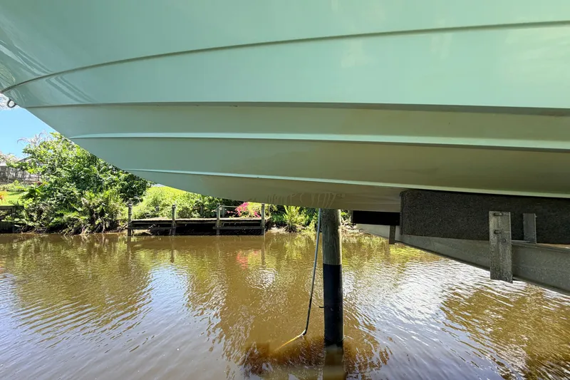 Slide: The Image of 2015 Pathfinder 2300 HPS boat hull above water, docked near lush greenery. - 6