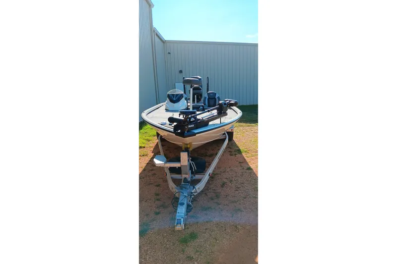 Slide: The Image of 2025 Ranger ALPHA 208 boat on trailer, parked outdoors near metal building. - 2