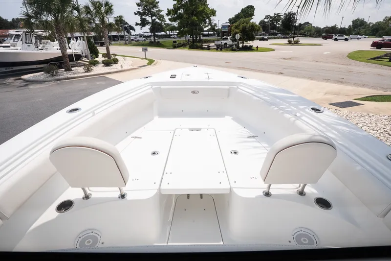 Slide: The Image of 2022 Sea Hunt Ultra 265SE boat interior with seating and table, parked outdoors. - 10