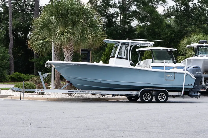 The Image of 2022 Sea Hunt Ultra 265SE boat on trailer, parked near palm trees. - 1