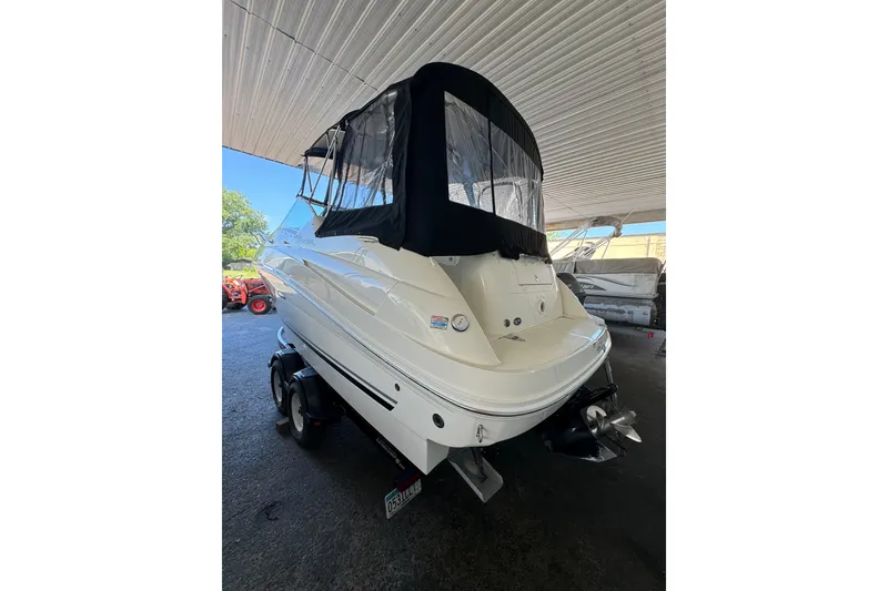 Slide: The Image of 2007 Sea Ray 240 Sundancer boat with black canopy, parked indoors on a trailer. - 21