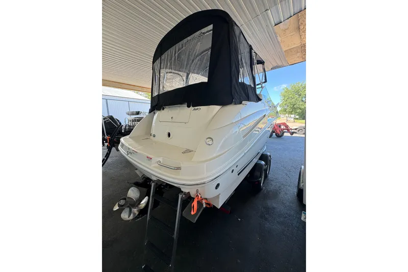 Slide: The Image of 2007 Sea Ray 240 Sundancer boat with black canopy, parked under a shelter. - 20