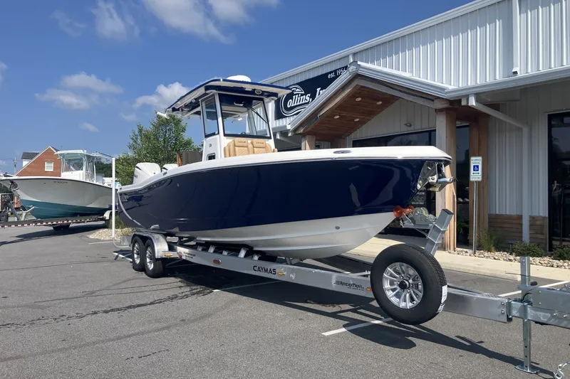 Slide: The Image of 2027 Caymas 291 boat on trailer outside dealership under blue sky. - 10