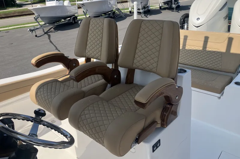 Slide: The Image of Luxury seating on 2027 Caymas 291 boat, featuring quilted upholstery and wooden armrests. - 17
