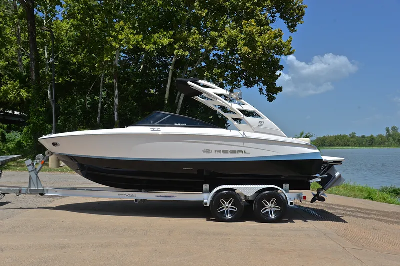 Slide: The Image of 2020 Regal LS2 Surf boat on trailer by a lakeside with trees. - 12