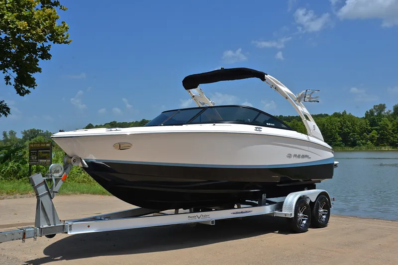 Slide: The Image of 2020 Regal LS2 Surf boat on trailer by a lake under clear blue sky. - 11