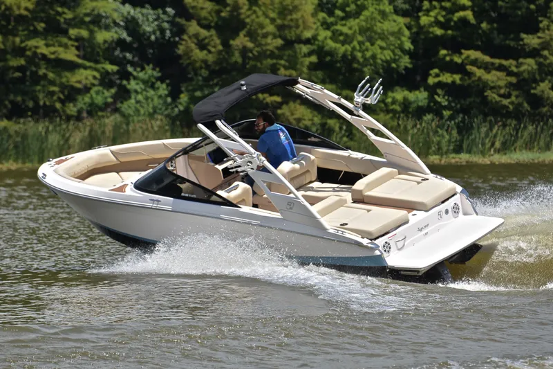 Slide: The Image of 2020 Regal LS2 Surf boat cruising on a lake with lush greenery in the background. - 6