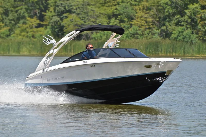 The Image of 2020 Regal LS2 Surf boat cruising on a lake with lush greenery in the background. - 1