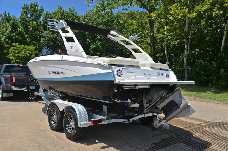 Slide: The Image of 2020 Regal LS2 Surf boat on trailer, parked outdoors near trees. - 13