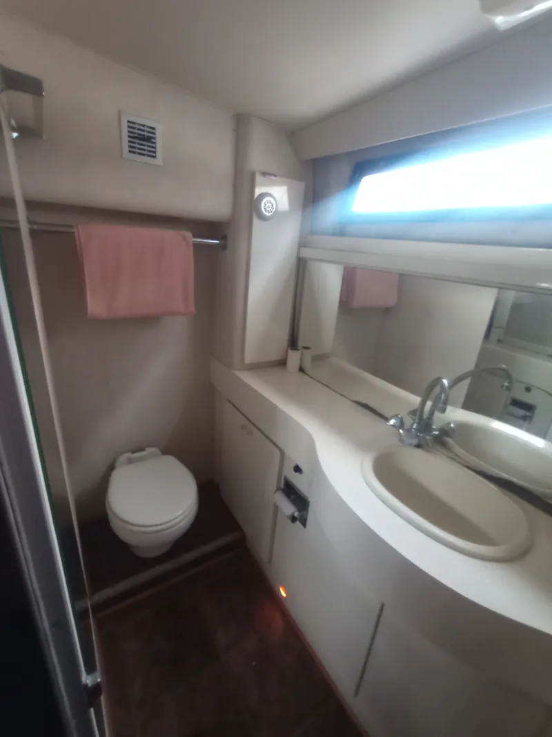 Slide: The Image of The image shows a bathroom in a 1991 Silverton AFT CABIN yacht with a sink and toilet. - 35