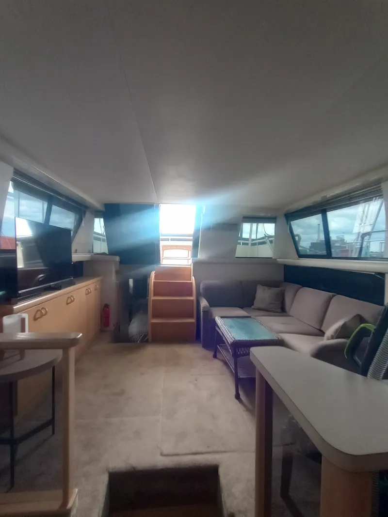 Slide: The Image of Interior of a 1991 Silverton AFT CABIN with sofa, table, and stairs leading to an elevated area. - 31