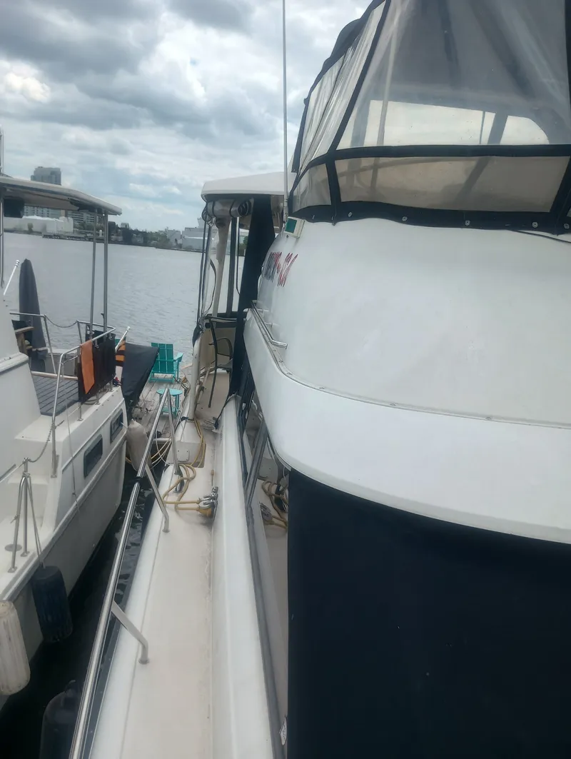 Slide: The Image of A 1991 Silverton AFT CABIN boat docked. It features a covered upper deck. - 8