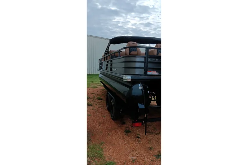 Slide: The Image of 2026 Ranger 220F pontoon boat, rear view, parked on gravel near a building. - 4