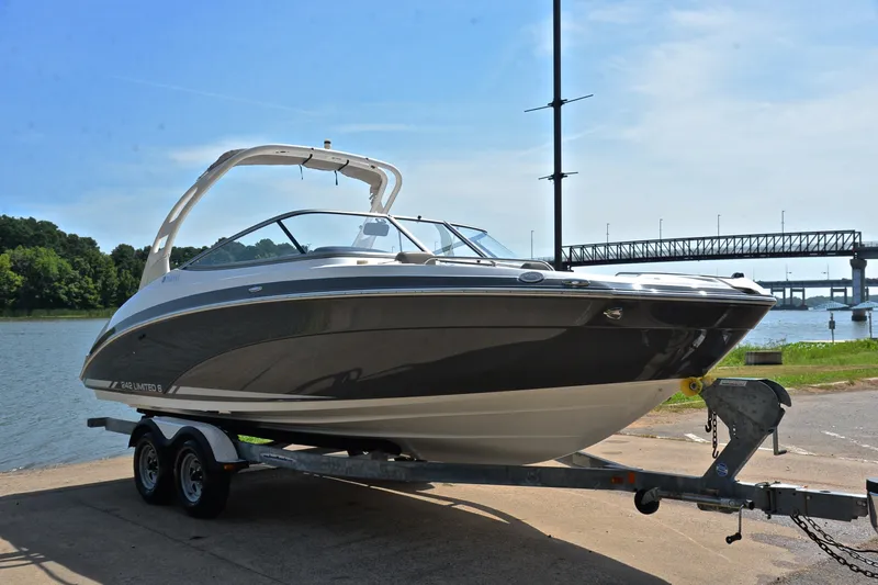 Slide: The Image of 2015 Yamaha Boats 242 Limited S on trailer by a river, bridge in background. - 15