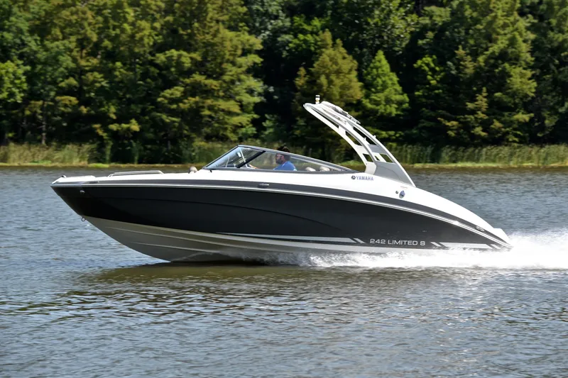 Slide: The Image of 2015 Yamaha Boats 242 Limited S cruising on a serene lake with lush greenery. - 2