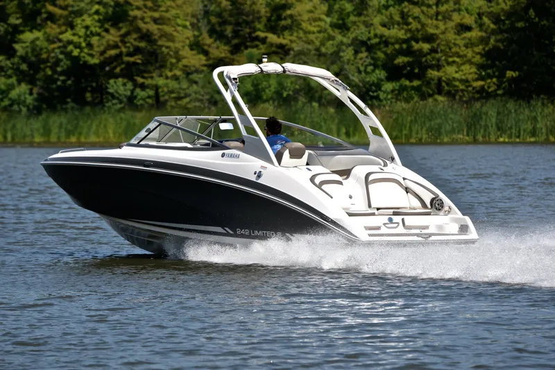 Slide: The Image of 2015 Yamaha Boats 242 Limited S cruising on a serene lake with lush greenery. - 4