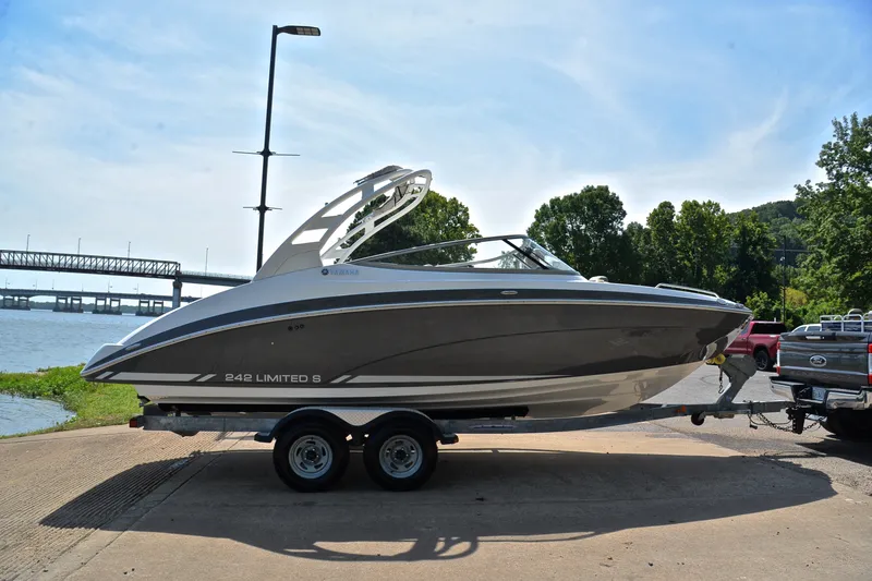Slide: The Image of 2015 Yamaha Boats 242 Limited S on trailer by riverside, sunny day. - 14