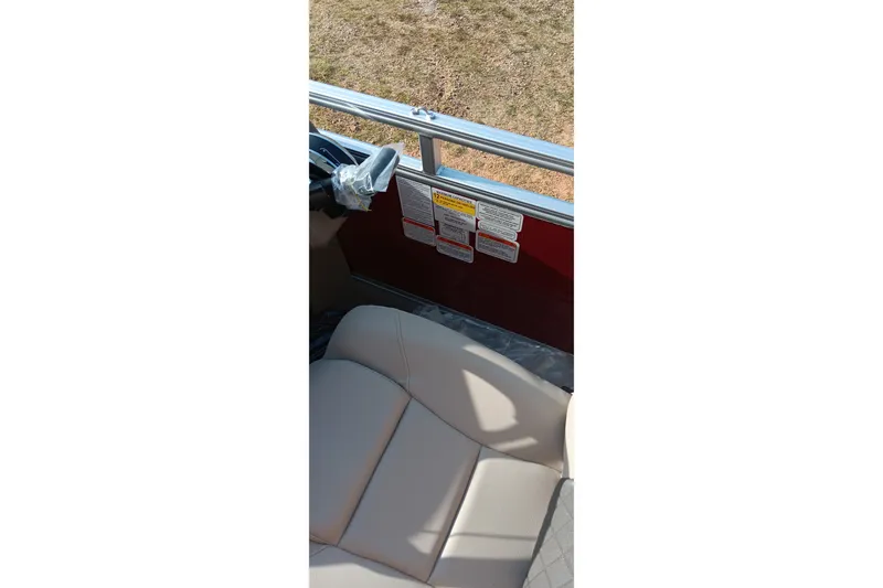 Slide: The Image of 2025 Sun Tracker Party Barge 24 DLX interior with beige seating and safety labels. - 9