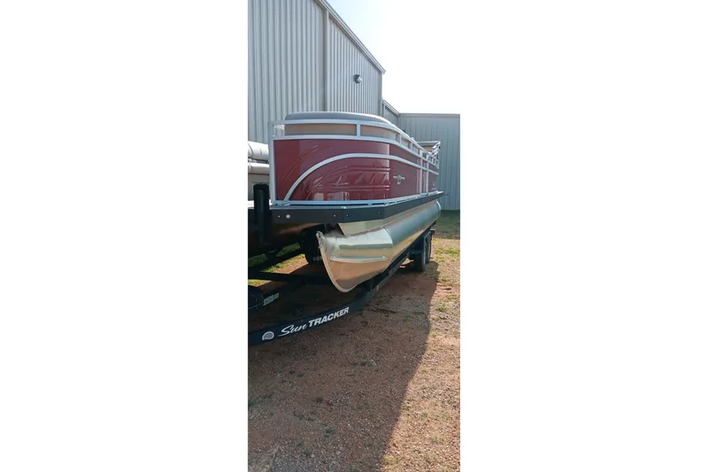 Slide: The Image of 2025 Sun Tracker Party Barge 24 DLX pontoon boat on trailer, parked outdoors. - 19