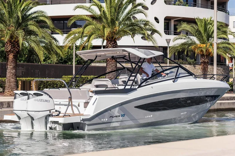 Slide: The Image of Manufacturer Provided Image: 2026 Beneteau Flyer 10 boat cruising near palm trees and modern architecture. - 2